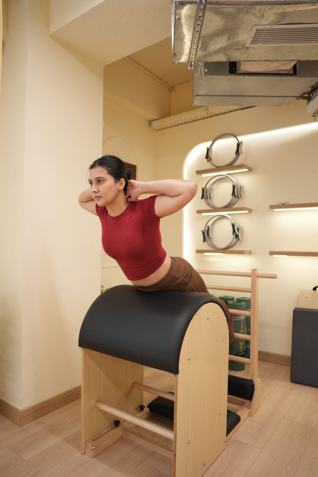 Client extending over the ladder barrel, hands behind the head, at Veda Pilates